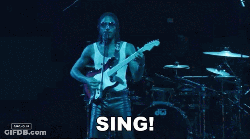 A Man Singing Into A Microphone While Playing A Guitar In Front Of A Dw Drum Set GIF