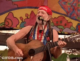 A Man Singing Into A Microphone While Playing A Guitar . GIF