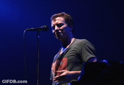 A Man Singing Into A Microphone While Wearing A Shirt That Says ' The Rolling Stones ' On It GIF