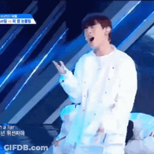 A Man Singing Into A Microphone While Wearing A White Shirt GIF