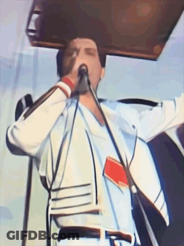 A Man Singing Into A Microphone While Wearing A White Shirt GIF