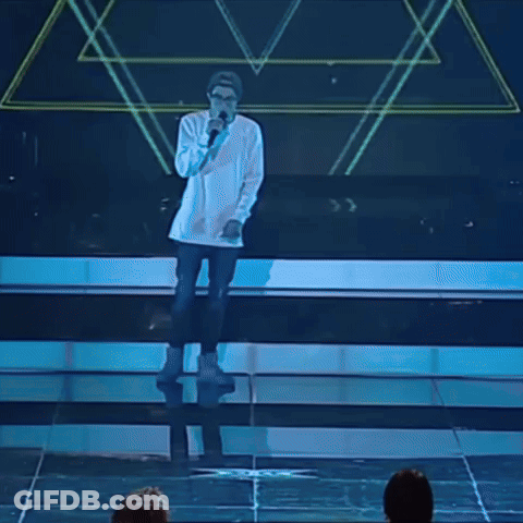 A Man Singing Into A Microphone While Wearing Glasses And A Hat GIF