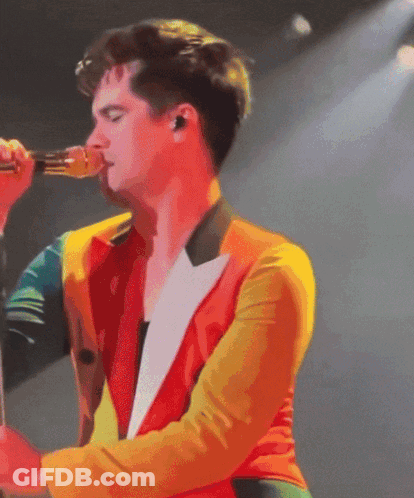 A Man Singing Into A Microphone With A Colorful Jacket On GIF