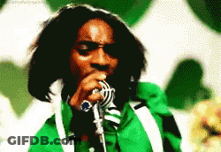 A Man Singing Into A Microphone With A Green Jacket On GIF