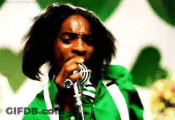 A Man Singing Into A Microphone With A Green Jacket On GIF