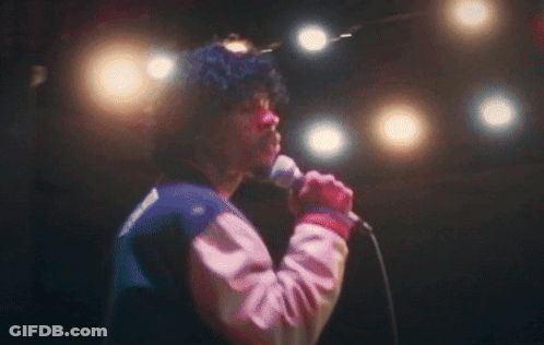 A Man Singing Into A Microphone With A Jacket That Has The Word Reebok On It GIF