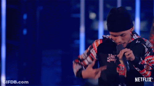 A Man Singing Into A Microphone With A Netflix Logo On The Bottom Right GIF