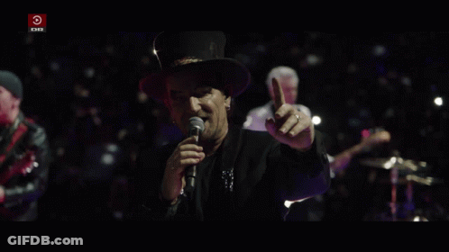 A Man Singing Into A Microphone With A Red Circle That Says Dr On It GIF