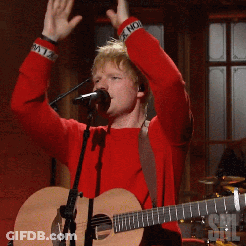 A Man Singing Into A Microphone With His Arms In The Air GIF