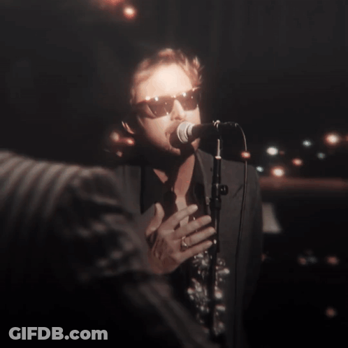 A Man Singing Into A Microphone With His Eyes Closed GIF