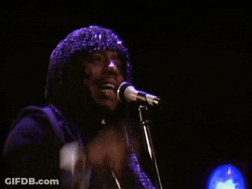 A Man Singing Into A Microphone With His Fist Up GIF