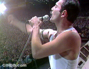A Man Singing Into A Microphone With His Mouth Open GIF