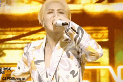 A Man Singing Into A Microphone With Korean Writing On The Screen GIF