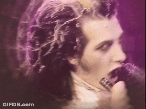 A Man Singing Into A Microphone With Purple Hair GIF