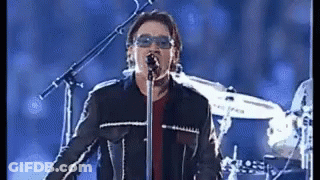 A Man Singing Into A Microphone With Sunglasses On GIF