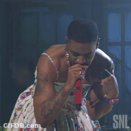 A Man Singing Into A Microphone With The Snl Logo In The Corner GIF