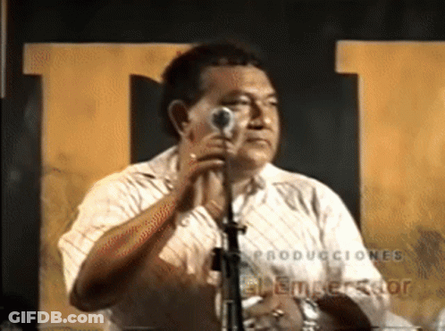 A Man Singing Into A Microphone With The Word Producciones On The Bottom Right GIF
