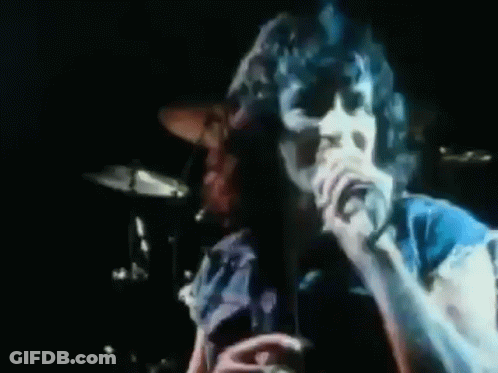 A Man Singing Into A Microphone With The Word Seems In Red GIF