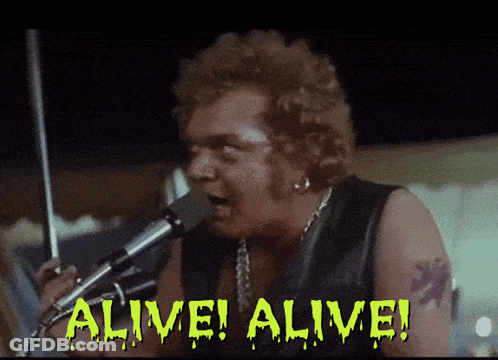 A Man Singing Into A Microphone With The Words Alive Alive Written On The Screen GIF