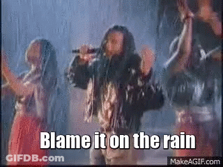 A Man Singing Into A Microphone With The Words Blame It On The Rain Above Him GIF
