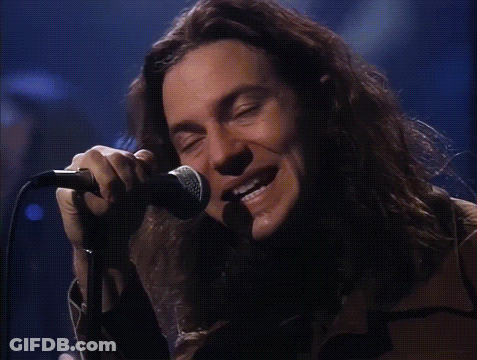 A Man Singing Into A Microphone With The Words He Looks Insane Behind Him GIF
