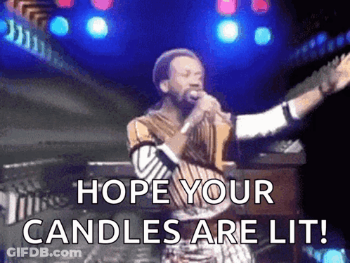 A Man Singing Into A Microphone With The Words Hope Your Candles Are Lit Written Below Him GIF