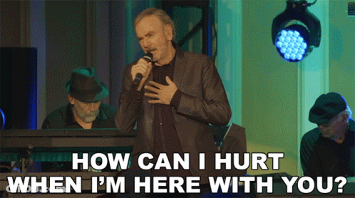 A Man Singing Into A Microphone With The Words " How Can I Hurt When I 'M Here With You " GIF