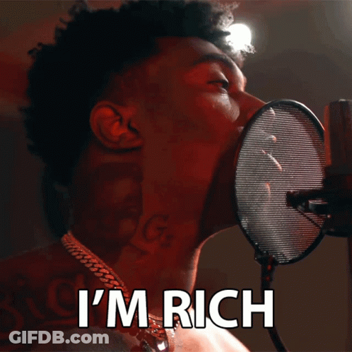 A Man Singing Into A Microphone With The Words I 'M Rich Behind Him GIF