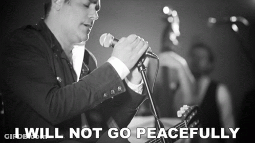 A Man Singing Into A Microphone With The Words " I Will Not Go Peacefully " Next To Him GIF