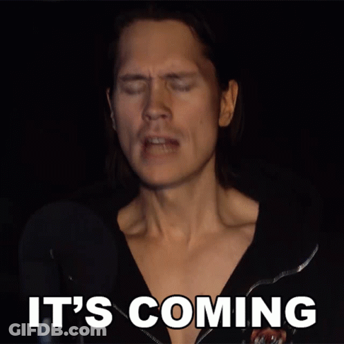 A Man Singing Into A Microphone With The Words It 'S Coming Above Him GIF
