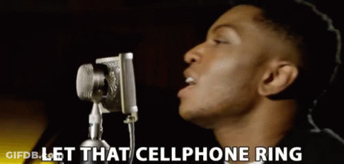 A Man Singing Into A Microphone With The Words Let That Cellphone Ring Behind Him GIF