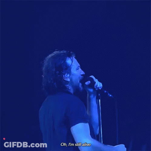 A Man Singing Into A Microphone With The Words Oh , I 'M Still Alive Below Him GIF