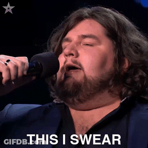 A Man Singing Into A Microphone With The Words " This I Swear " Behind Him GIF