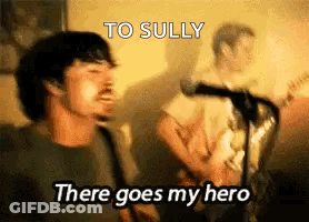 A Man Singing Into A Microphone With The Words `` To Sully There Goes My Hero '' Behind Him . GIF