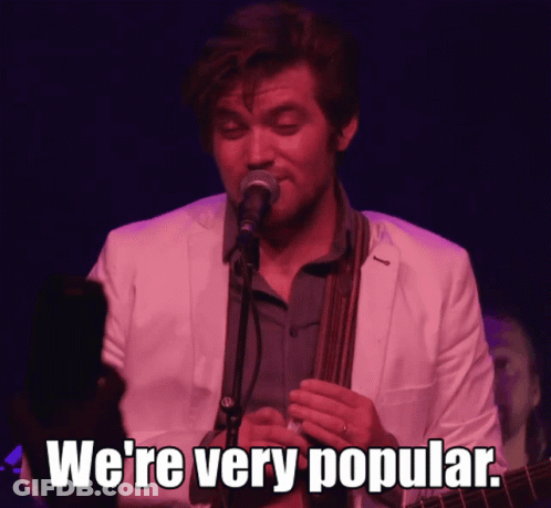 A Man Singing Into A Microphone With The Words " We 'Re Very Popular " Next To Him GIF