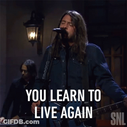 A Man Singing Into A Microphone With The Words You Learn To Live Again Behind Him GIF