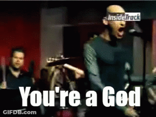 A Man Singing Into A Microphone With The Words " You 'Re A God " Behind Him GIF