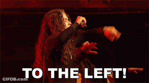 A Man Singing Into A Microphone With To The Left Written Below Him GIF