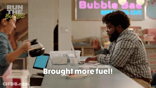 A Man Sits At A Counter In Front Of A Sign That Says Bubble Day GIF