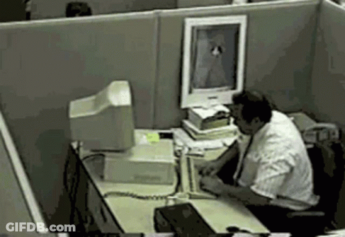 A Man Sits At A Desk In Front Of A Computer Screen GIF