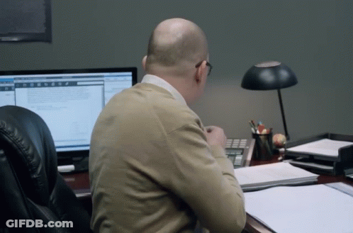 A Man Sits At A Desk In Front Of A Computer Screen GIF