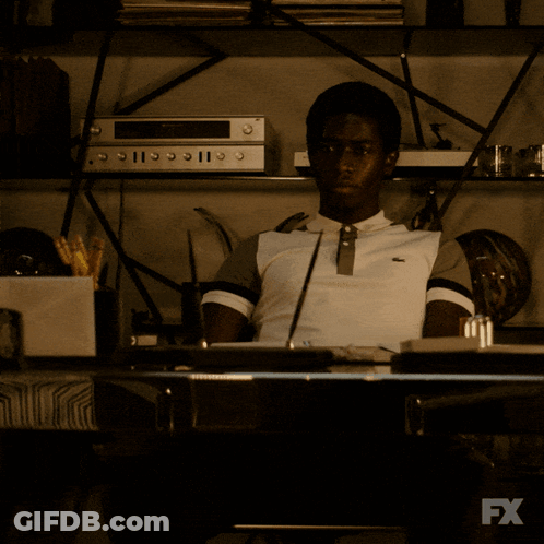 A Man Sits At A Desk In Front Of A Tv That Says Fx GIF