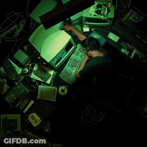 A Man Sits At A Desk With A Computer And A Keyboard That Says " Microsoft " On It GIF