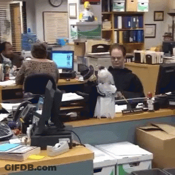 A Man Sits At A Desk With A White Parrot On His Lap GIF