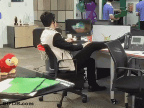 A Man Sits At A Desk With His Feet Up In Front Of A Computer Monitor GIF