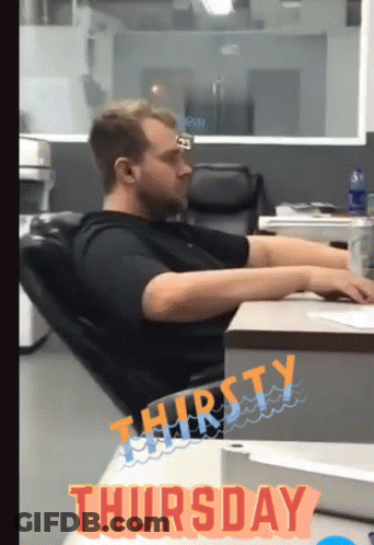 A Man Sits At A Desk With The Word Thursday On The Bottom GIF