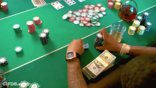 A Man Sits At A Poker Table With A Stack Of 100 Dollar Bills GIF