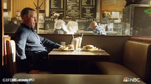 A Man Sits At A Table In A Diner With A Nbc Logo In The Corner GIF