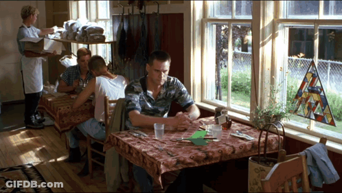 A Man Sits At A Table In Front Of A Stained Glass Window GIF
