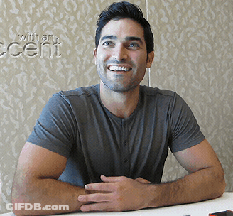 A Man Sits At A Table In Front Of A Wall That Has The Word Accent On It GIF